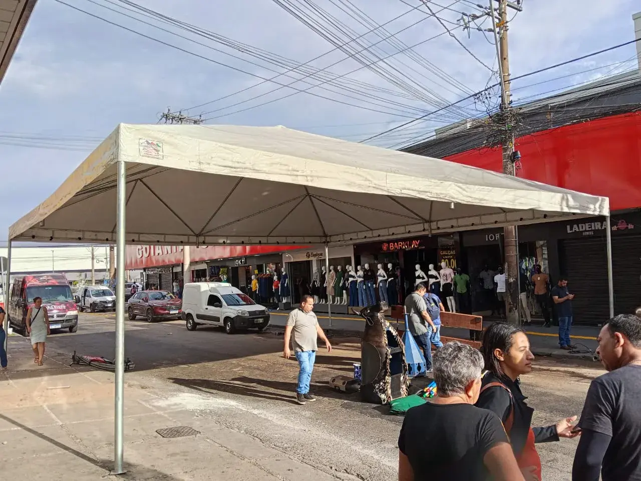 Tenda branca montada em rua comercial em frente a lojas